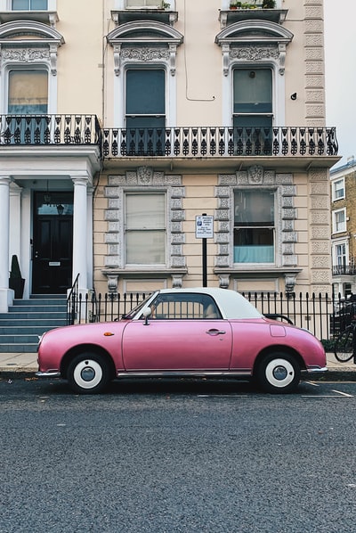 A red car parked in front of the white building
